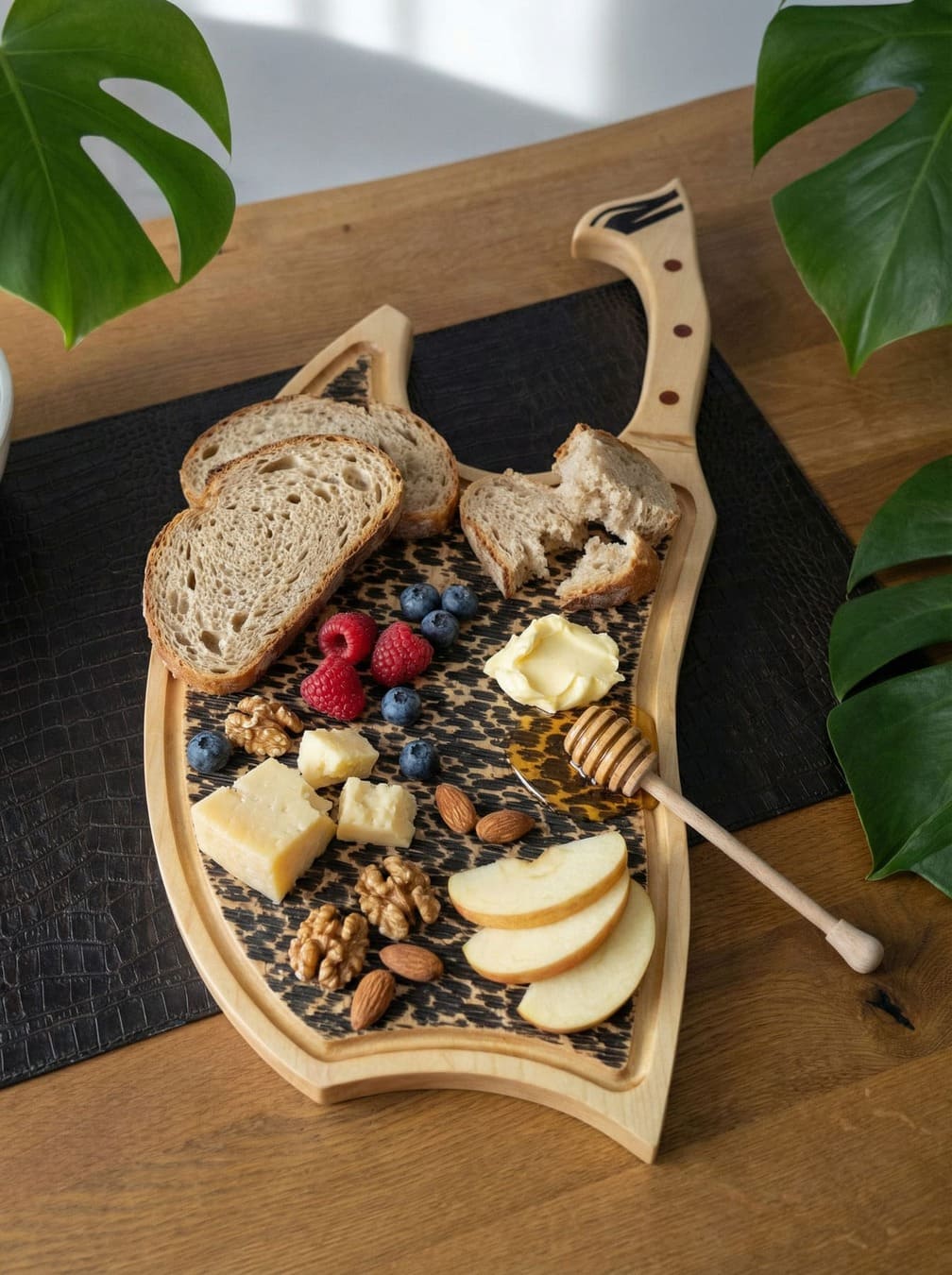 Nordic Breakfast Board mit Sauerteigbrot, Beeren, Käse, Nüssen, Apfelspalten und Honig auf einem Ahorn-Axtbrett