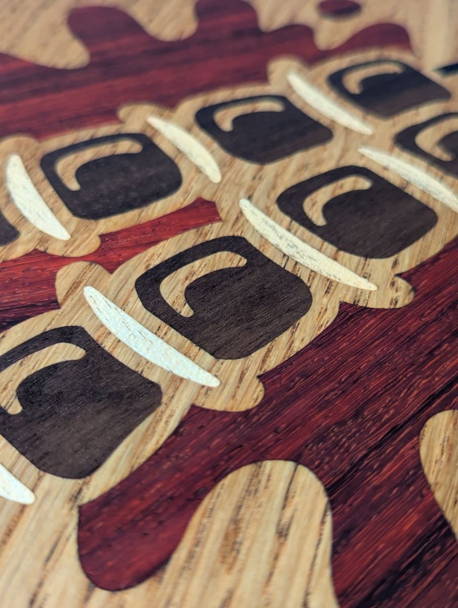 Nahaufnahme Holz-Inlay aus Padouk, Ahorn und Nussbaum – Schaschlik-Motiv auf Eichengrund